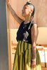 Side view of Minnie Tank in Black paired with Jessie Stripe Skirt in Dijon on model leaning in doorway
