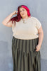 Model wearing Niko Sweater in Oat and Jessie Skirt in Mud/Black Stripe in front of gray wall