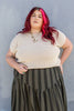Model wearing Niko Sweater in Oat and Jessie Skirt in Mud/Black Stripe in front of gray wall