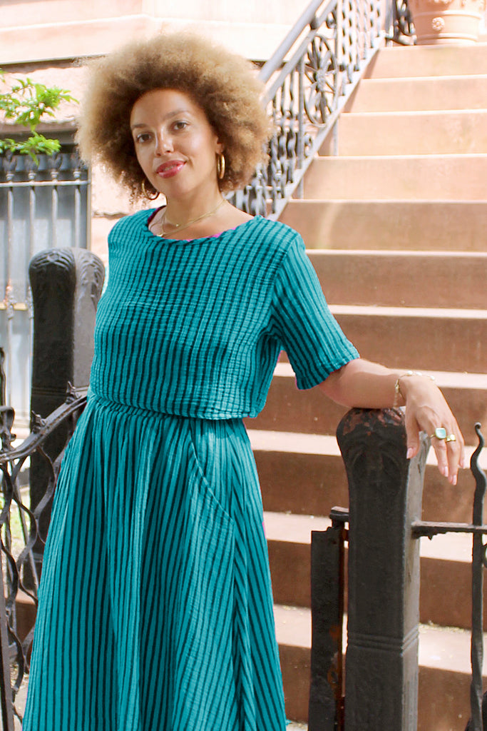 Noa Stripe Top in Ocean, paired with Fawn Stripe Skirt in Ocean, on model standing in front of stairs.