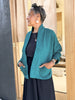 Oona Cardigan in Ocean on model, with hands in pockets, in front of wooden doorway.