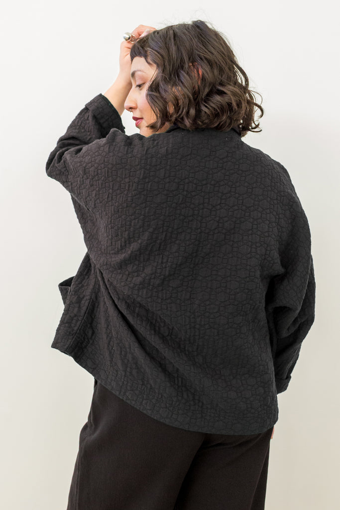 Back view of model wearing Oona Cardigan in Black in front of white background