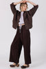 Front view of model wearing Oona Cardigan in Chocolate, Ayana Top in Mist, and Atlas Pant in Chocolate, standing  in front of white wall