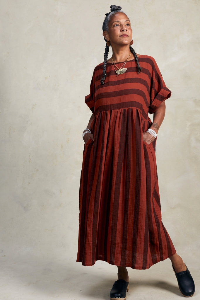 Perry Stripe Dress in Brick on model with hands in pockets in front of white background