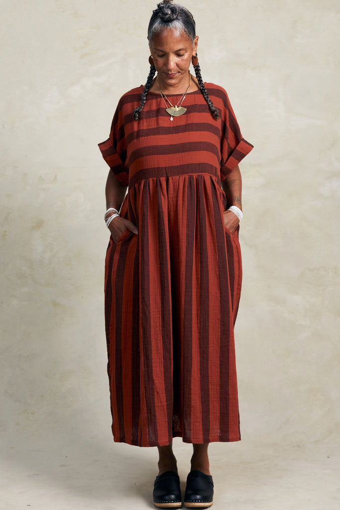 Perry Stripe Dress in Brick on model with hands in pockets in front of white background
