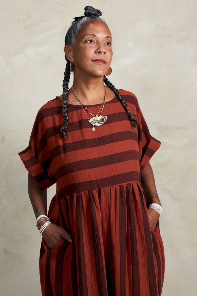 Perry Stripe Dress in Brick on model with hands in pockets in front of white background