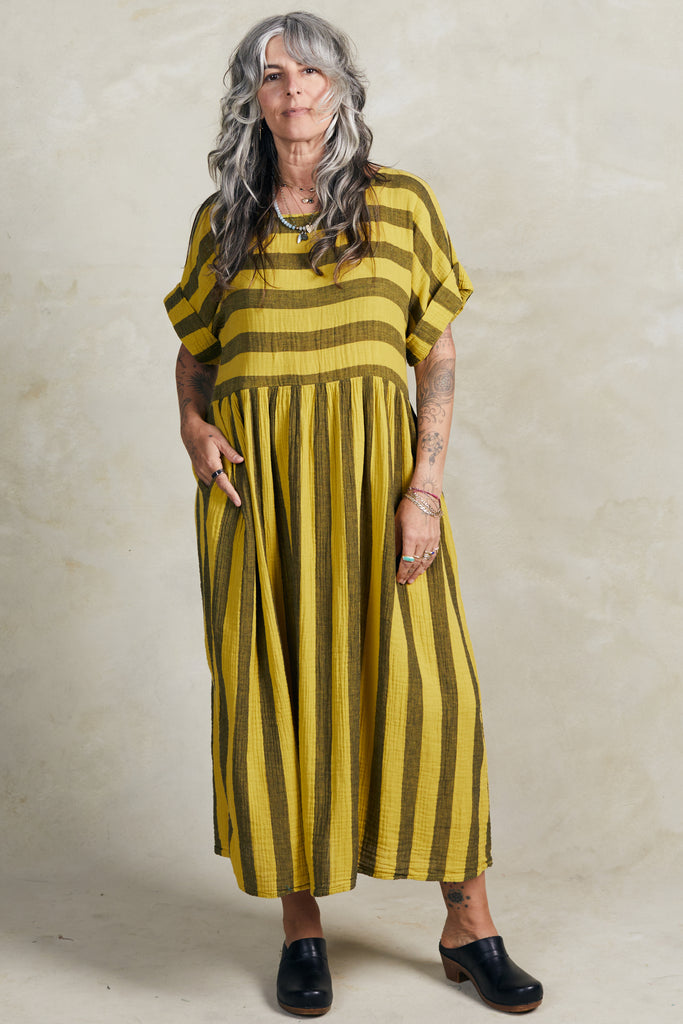 Model wearing Perry Stripe Dress in Dijon, standing with one hand in a pocket, in front of white background