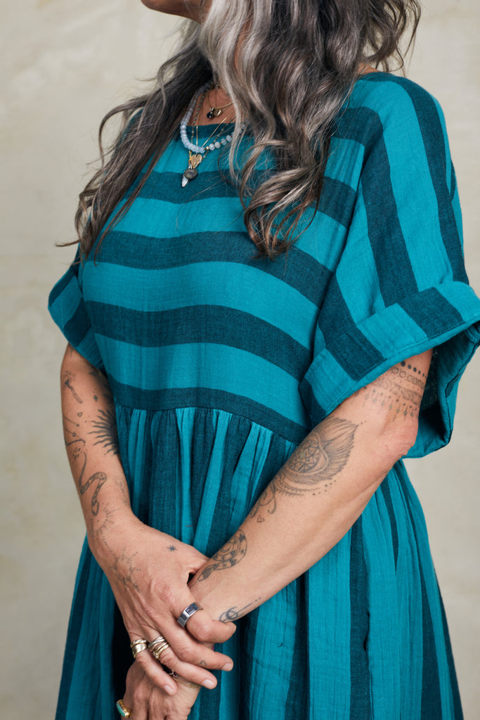 Close up of Perry Stripe Dress in Ocean on model with hands crossed in front of them, in front of white background
