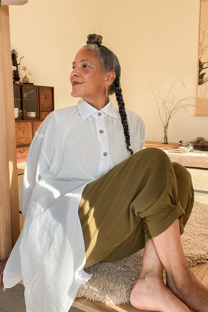 Model sitting and wearing Long Poet Blouse in White with Cadence Pants in Fennel 