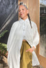 Model wearing Long Poet Blouse in White and Cadence Pants in Fennel standing with hand in pocket in front of grey building