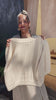 Video of model putting on Maeva Cardigan in Biscuit in front of grey building