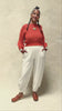 Video of model wearing Lana Sweater in Tomato and Cadence Pant in White, slowly turning in front of white background