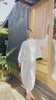Video of model wearing Cropped Poet Blouse in White and Cadence Pants in White, showing different angles and closeups of shirt buttons, in front of grey building 