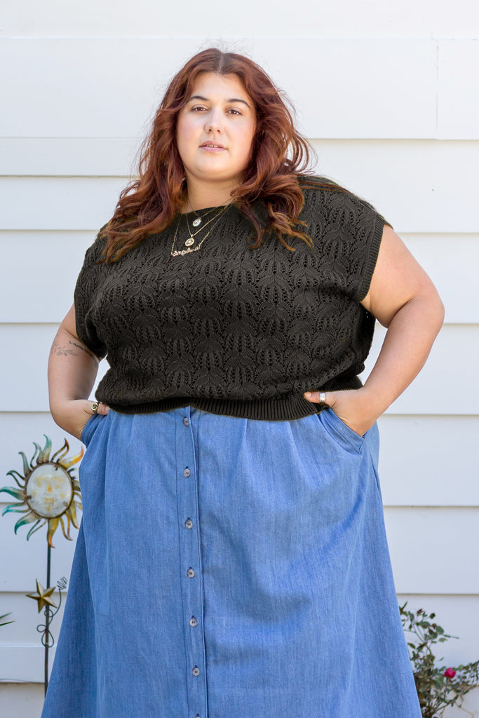 Model wearing Rosey Sweater in Black and Bonnie Skirt in Light Denim in front of white wall