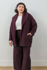 Front view of model wearing Sadie Coat in Burgundy, Ayana Top in White, and Dover Pant in Burgundy, with one hand in pocket in front of white background