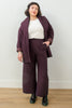 Front view of model wearing Sadie Coat in Burgundy, Ayana Top in White, and Dover Pant in Burgundy, with one hand in pants pocket in front of white background