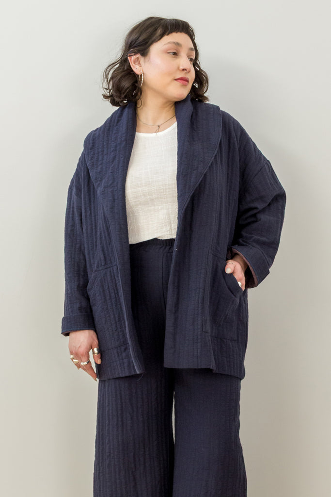 Front view of model wearing Sadie Coat in Indigo, Ayana Top in White, and Dover Pant in Indigo, with one hand in pocket in front of white background