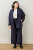 Front view of model wearing Sadie Coat in Indigo, Ayana Top in White, and Dover Pant in Indigo, with one hand in jacket pocket in front of white background