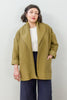 Front view of model wearing Sadie Coat in Fennel, Ayana Top in White, and Dover Pant in Indigo, with one hand in jacket pocket in front of white background