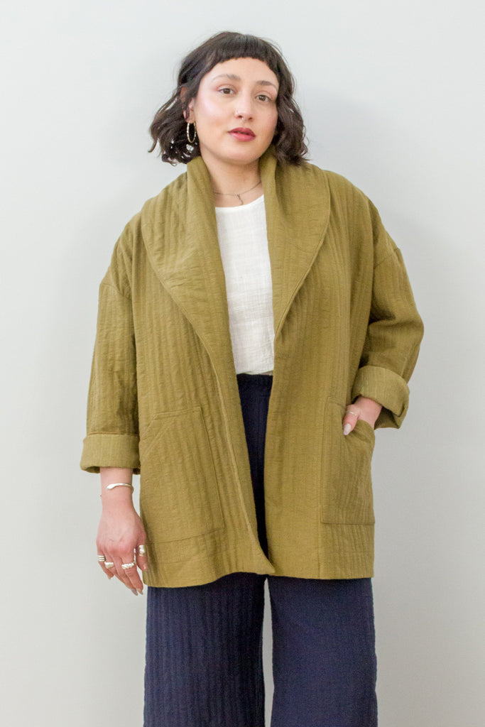 Front view of model wearing Sadie Coat in Fennel, Ayana Top in White, and Dover Pant in Indigo, with one hand in jacket pocket in front of white background