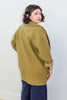 Back view of model wearing Sadie Coat in Fennel and Dover Pant in Indigo, in front of white background