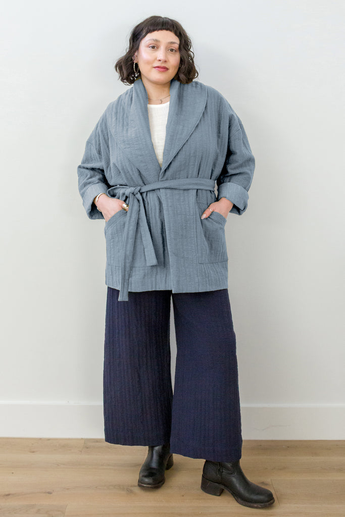 Sadie Coat in Stone on model. Woman wearing a light blue jacket over a white top and dark pants on a plain background.