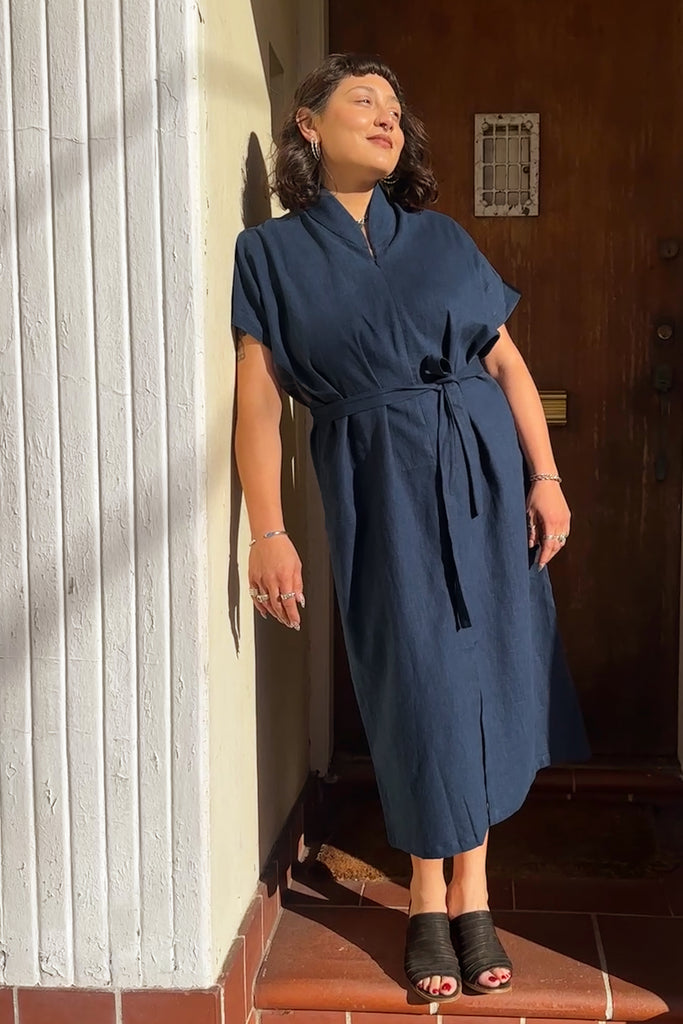 Vela Caftan in Peacoat with tie belt on model leaning against white wall