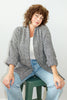 Model wearing Sloane Coat in Black/White and light wash jeans sitting on green stool in front of white wall