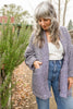 Model wearing Sloane Coat in Black/White, and light wash jeans next to green foliage