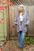Model wearing Sloane Coat in Black/White, and light wash jeans in front of wooden fence