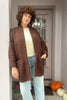 Front view of Sloane Coat in Cedar/Black paired with light denim on model standing with hand in pocket in building entryway