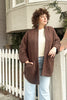 Front view of Sloane Coat in Cedar/Black paired with light denim on model with hand in pocket, leaning against white fence
