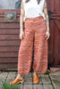 Model wearing Minnie Tank in White and Sofie Sweater Pants in Rust Melange in front of wooden structure