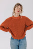 Model wearing Sonnie Sweater in Rust and light wash jeans with hands on hips in front of white background