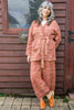 Model wearing Stevie Sweater and Sofie Sweater Pants in Rust Melange in front of wooden structure