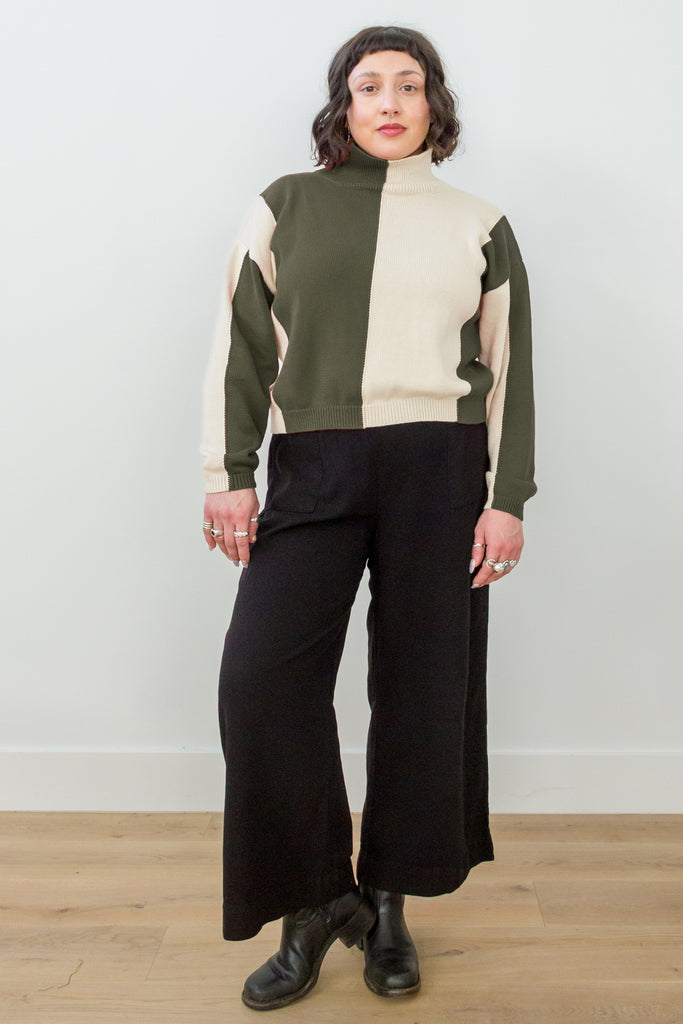 Front view of model wearing Sybil Vertical Stripe Sweater in Olive/Cream and Wide Leg Pant in Black, standing in front of white background