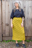 Model wearing Ayana Top in Black and Mae Sweater Skirt in Chartreuse in front of wooden wall