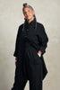 Front view of model wearing Workshirt and Cadence Pant both in Black, standing with one hand in pant pocket in front of white background