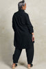 Back view of model wearing Workshirt and Cadence Pant both in Black, in front of white background