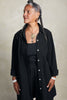Front view of model wearing Workshirt (open) and Cadence Pant both in Black, in front of white background