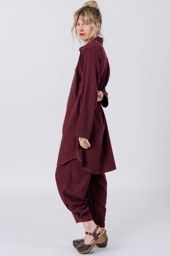 Side view of model wearing Workshirt and Cadence Pant both in Burgundy, in front of white background