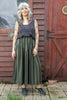Model wearing Zoe Tank in Charcoal and Jessie Skirt in Mud/Black Stripe in front of wooden building