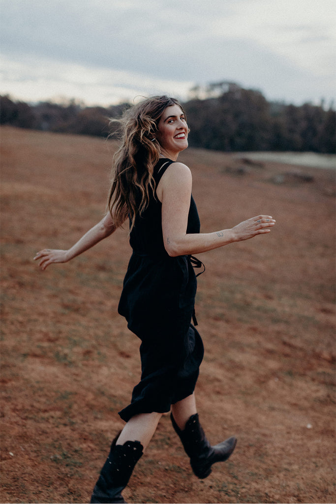 Walking model wearing black sleeveless dress and black boots