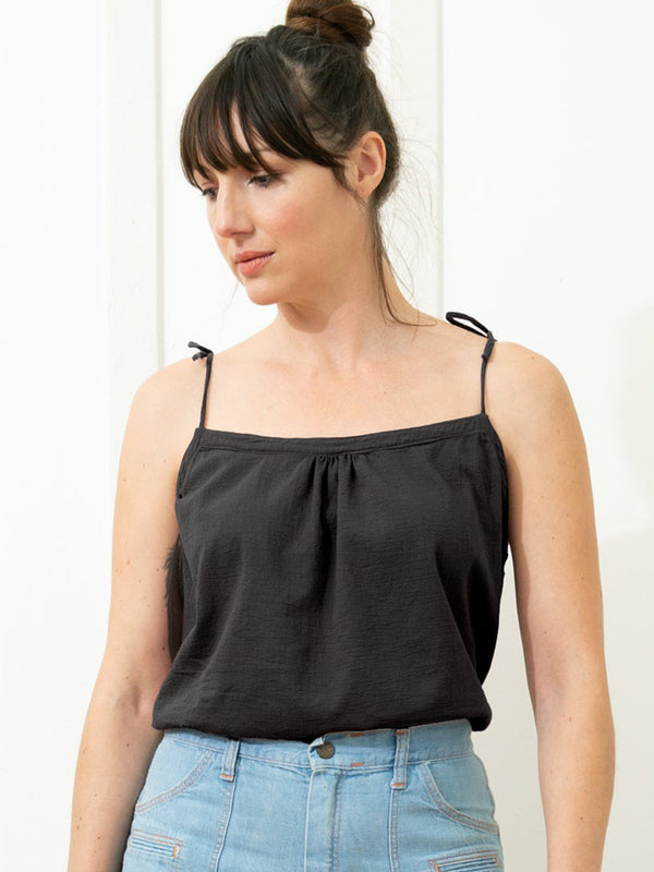 Model wearing black tie string tank top paired with light blue denim