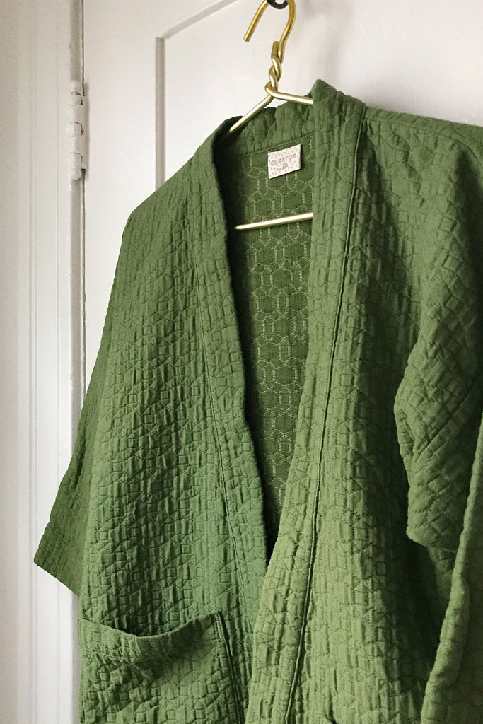 Close up photo of green quilted jacket on hanger