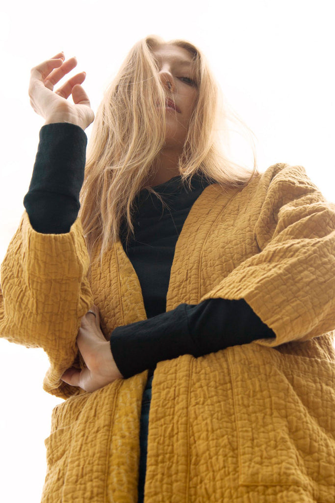close up of model in yellow quilted jacket and black long sleeve top